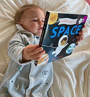 Baby reading a book about space